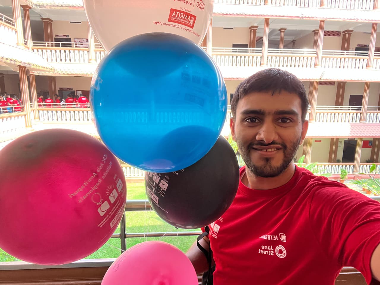 Harshit Tomar smiling, holding ICPC balloons at a programming contest